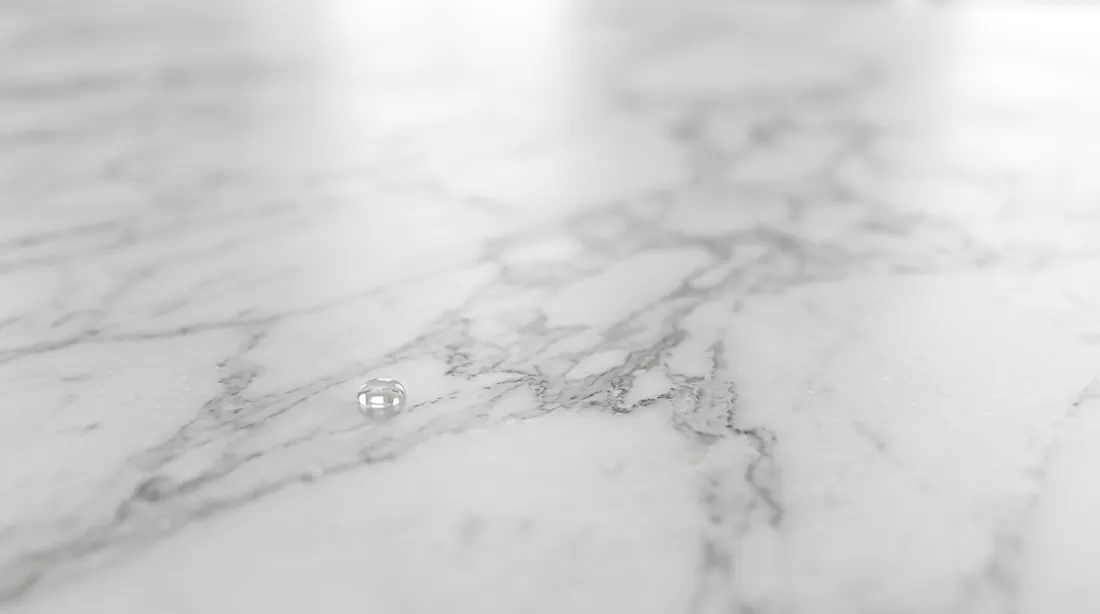 White marble surface with grey veining and a water droplet