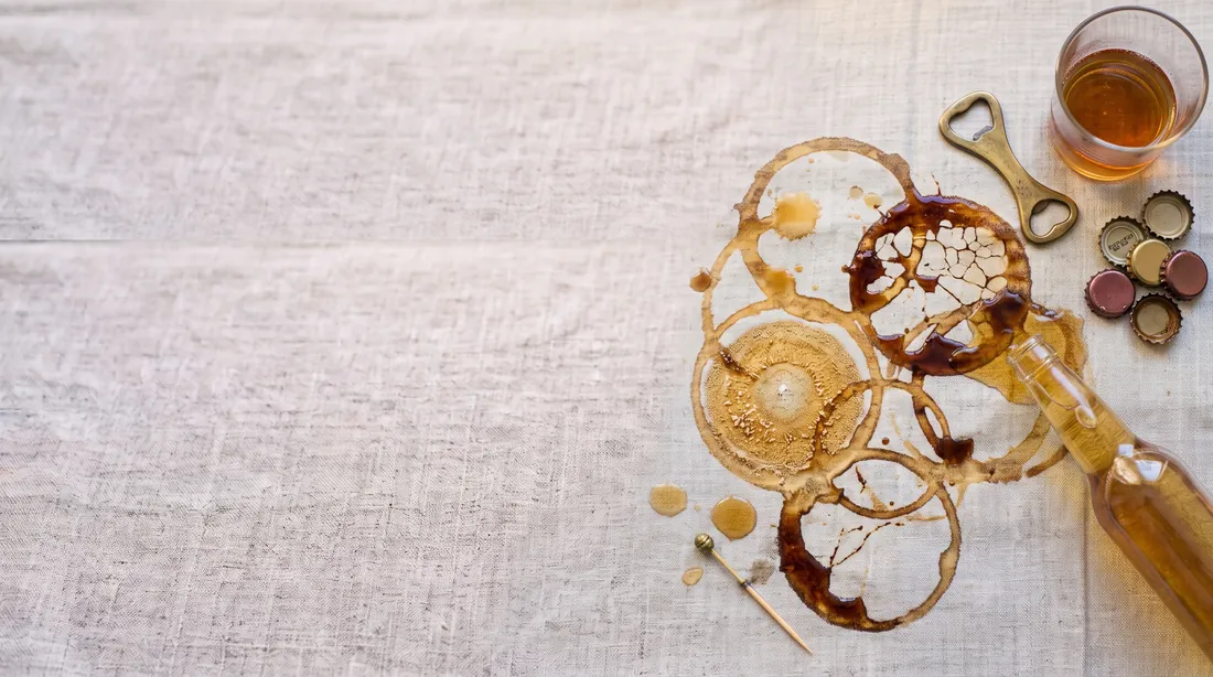 Beer glass rings and a tipped-over bottle on linen