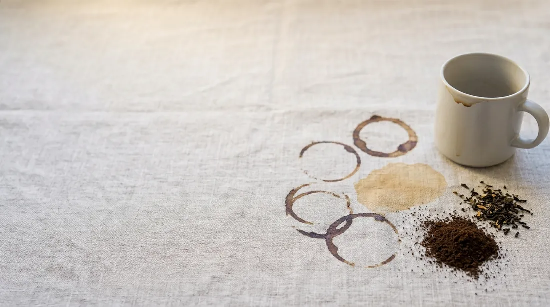 Coffee cup rings and spilled grounds beside a mug on linen