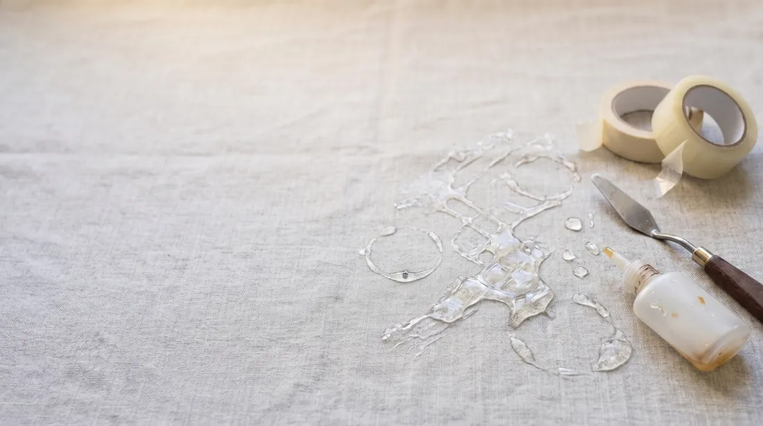 Dried clear glue smeared on linen with tape rolls and a putty knife