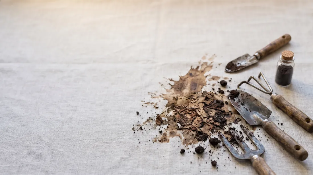 Dried mud and soil clumps on linen with garden hand tools