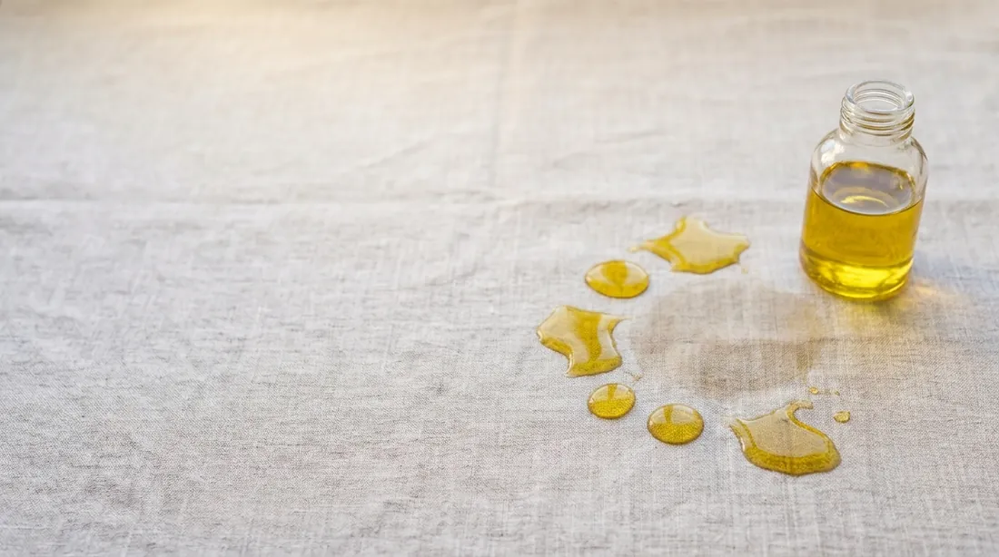 Cooking oil splashes beside an oil bottle on linen
