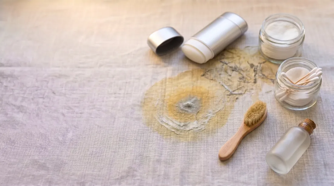 Yellowish sweat and deodorant marks on linen with a deodorant stick and jar